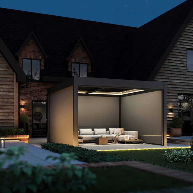 Dark grey pergola with LED roof lighting and fully retracted blinds, creating a cosy seating area on a garden patio at dusk.