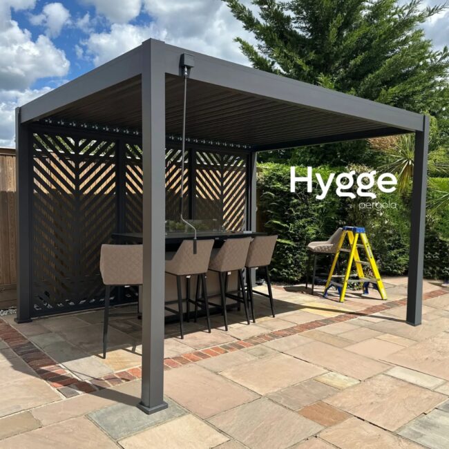 Dining space under a sleek aluminium pergola with integrated privacy screens and ambient lighting.