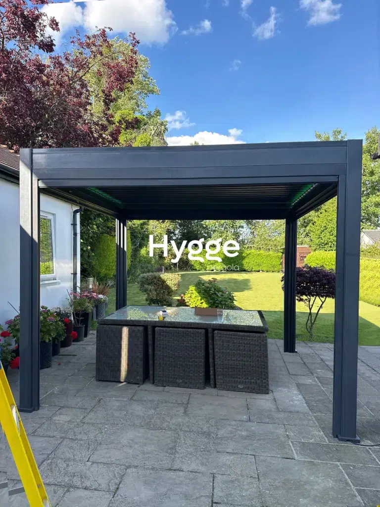 Modern dark grey aluminium pergola with privacy panels, installed on a patio with contemporary furnishings.