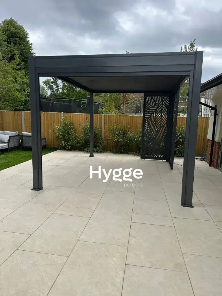 Spacious dark grey aluminium pergola with a built-in lounge area, creating a cosy retreat.