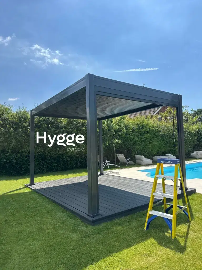 Luxury dark grey aluminium pergola with decorative slatted panels, creating a private outdoor dining space.