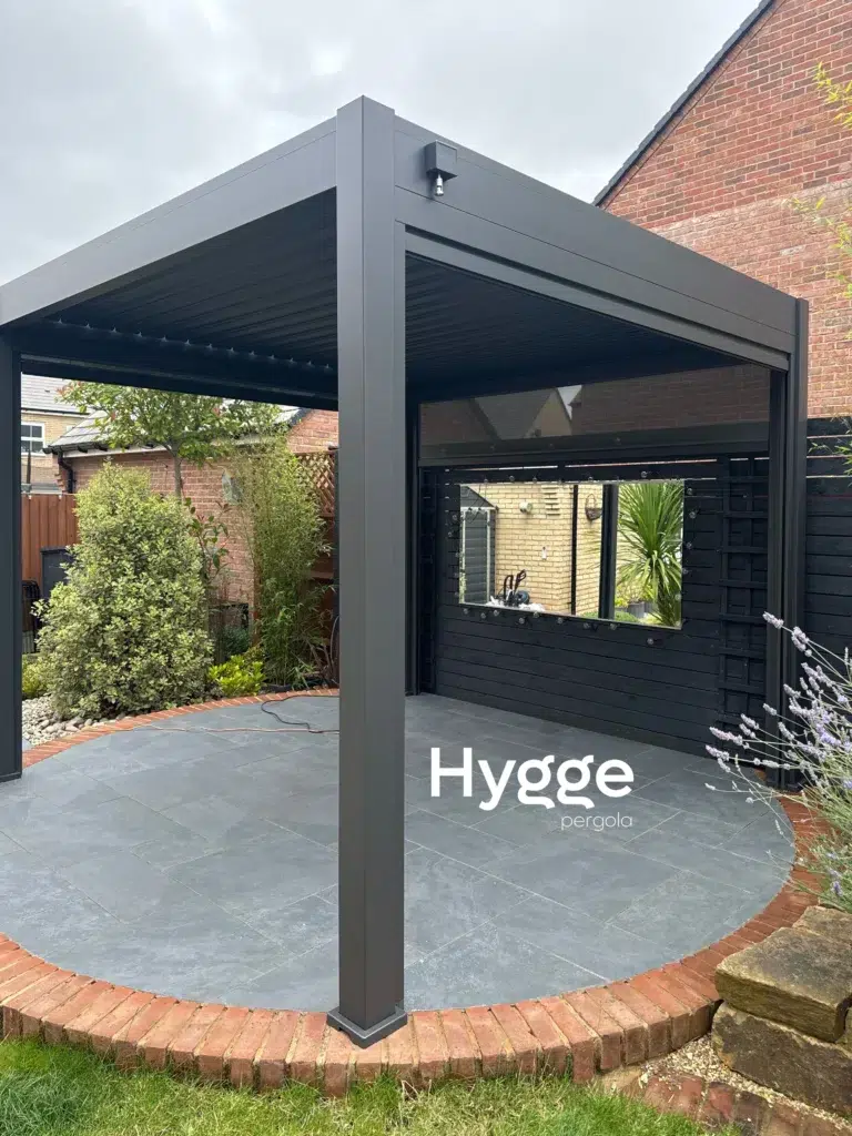 Contemporary dark grey aluminium pergola with a retractable louvred roof, installed in a garden patio.