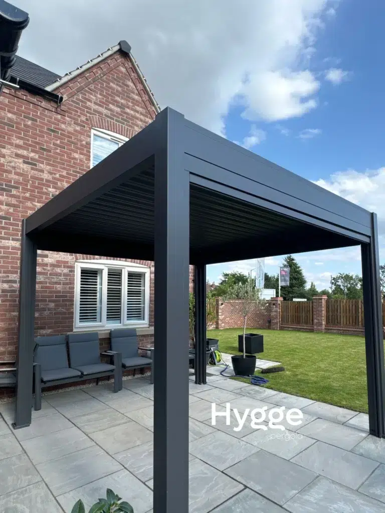 Dark grey aluminium pergola with a closed louvred roof, providing shade and rain protection.