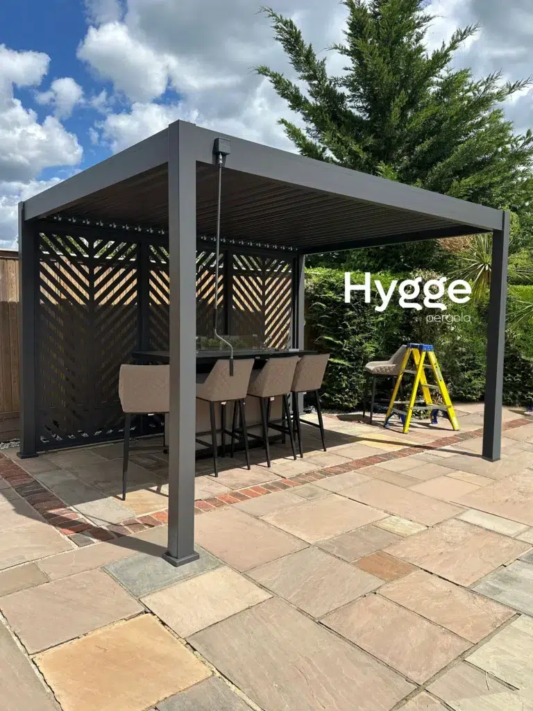 Freestanding dark grey aluminium pergola with an outdoor dining area, offering weather protection and style.